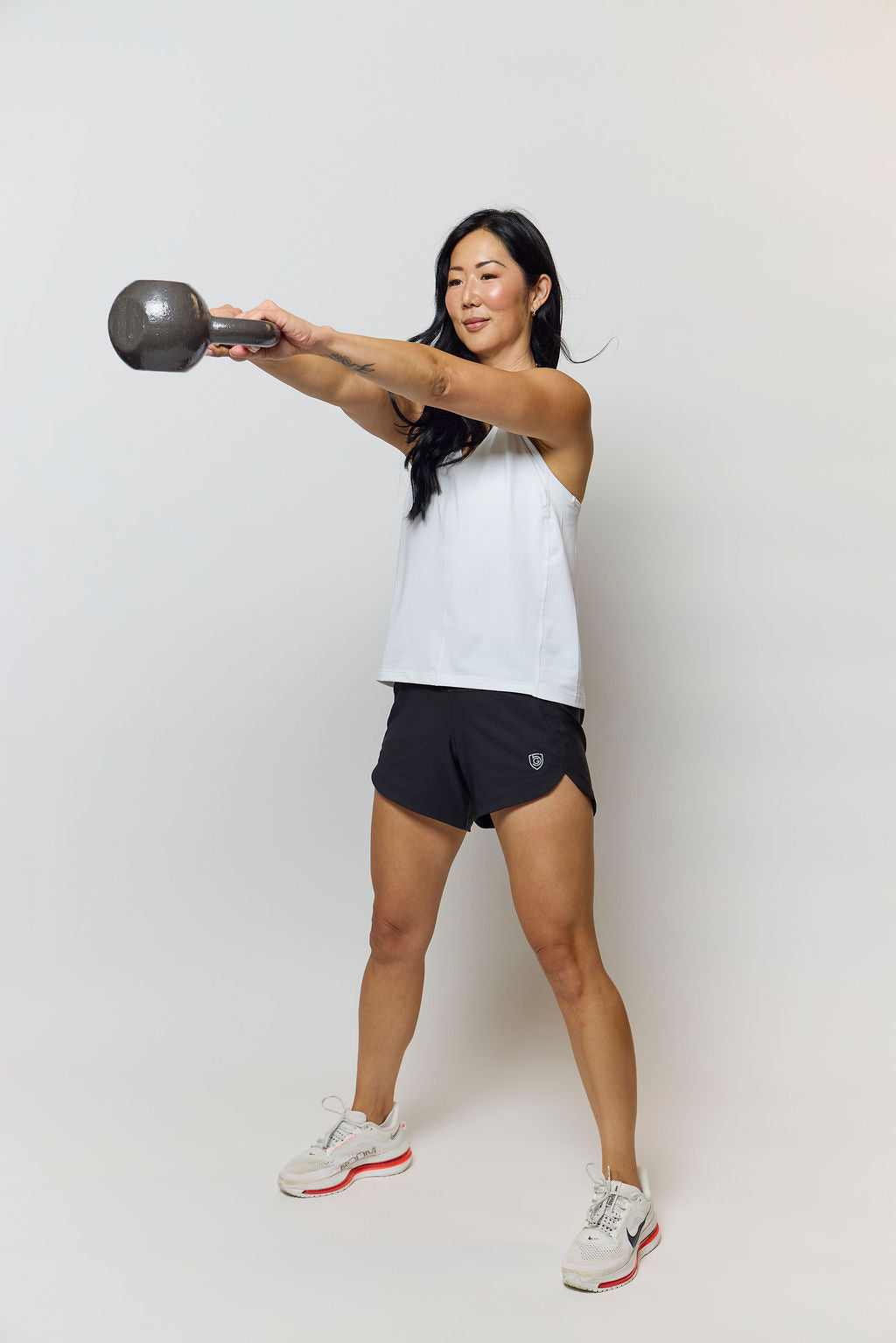 Women's Excel workout shorts in a relaxed training fit, showing extended hem length and waistband pocket detail