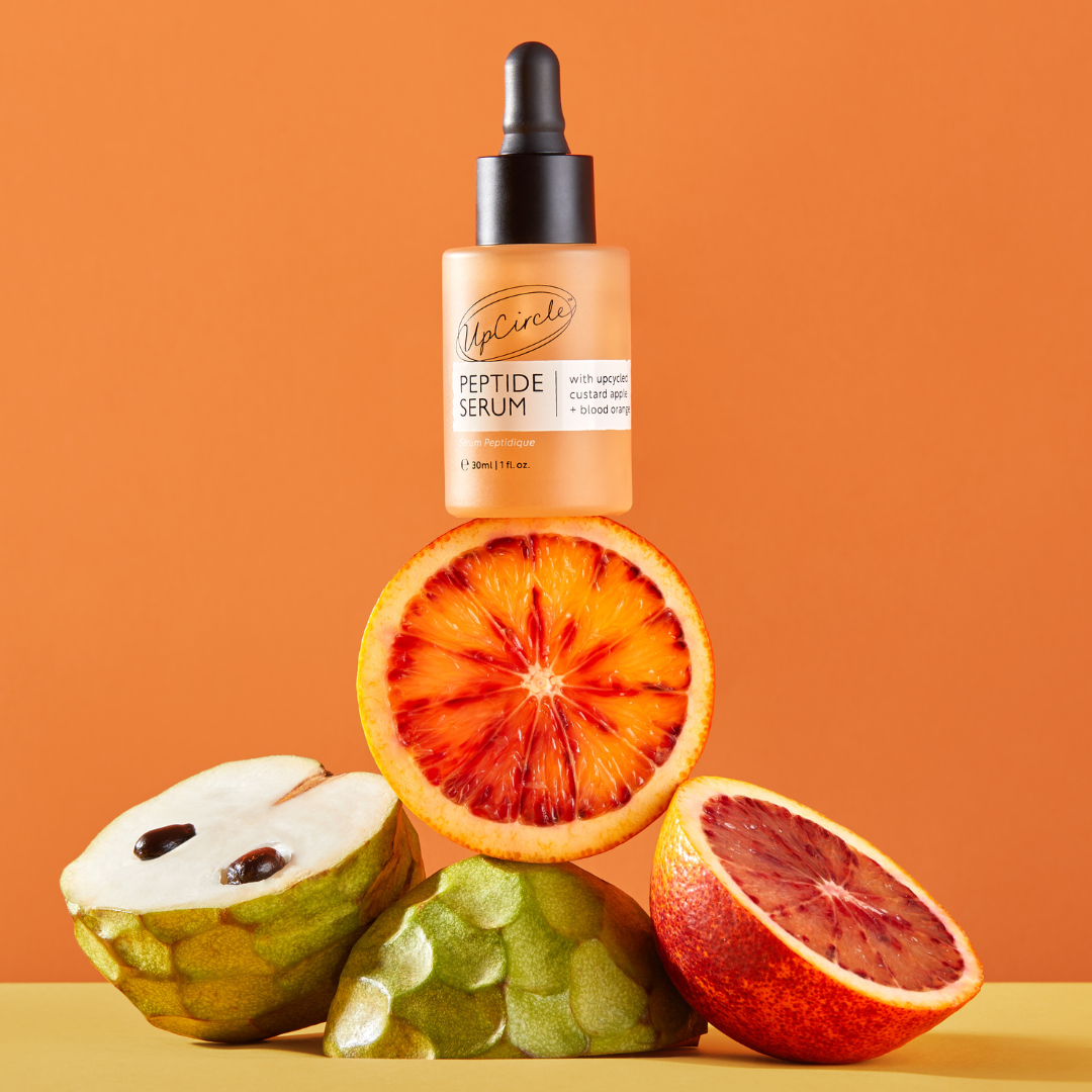 UpCircle Peptide Serum with Custard Apple and Blood Orange in a glass bottle, with a dropper and a skincare background