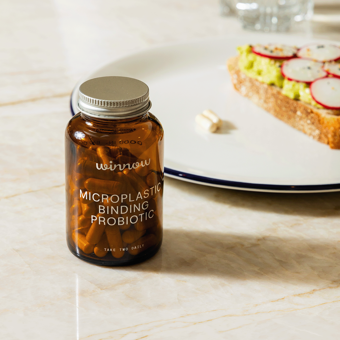 Daily probiotic starter kit in a reusable glass jar with white capsules and minimal packaging