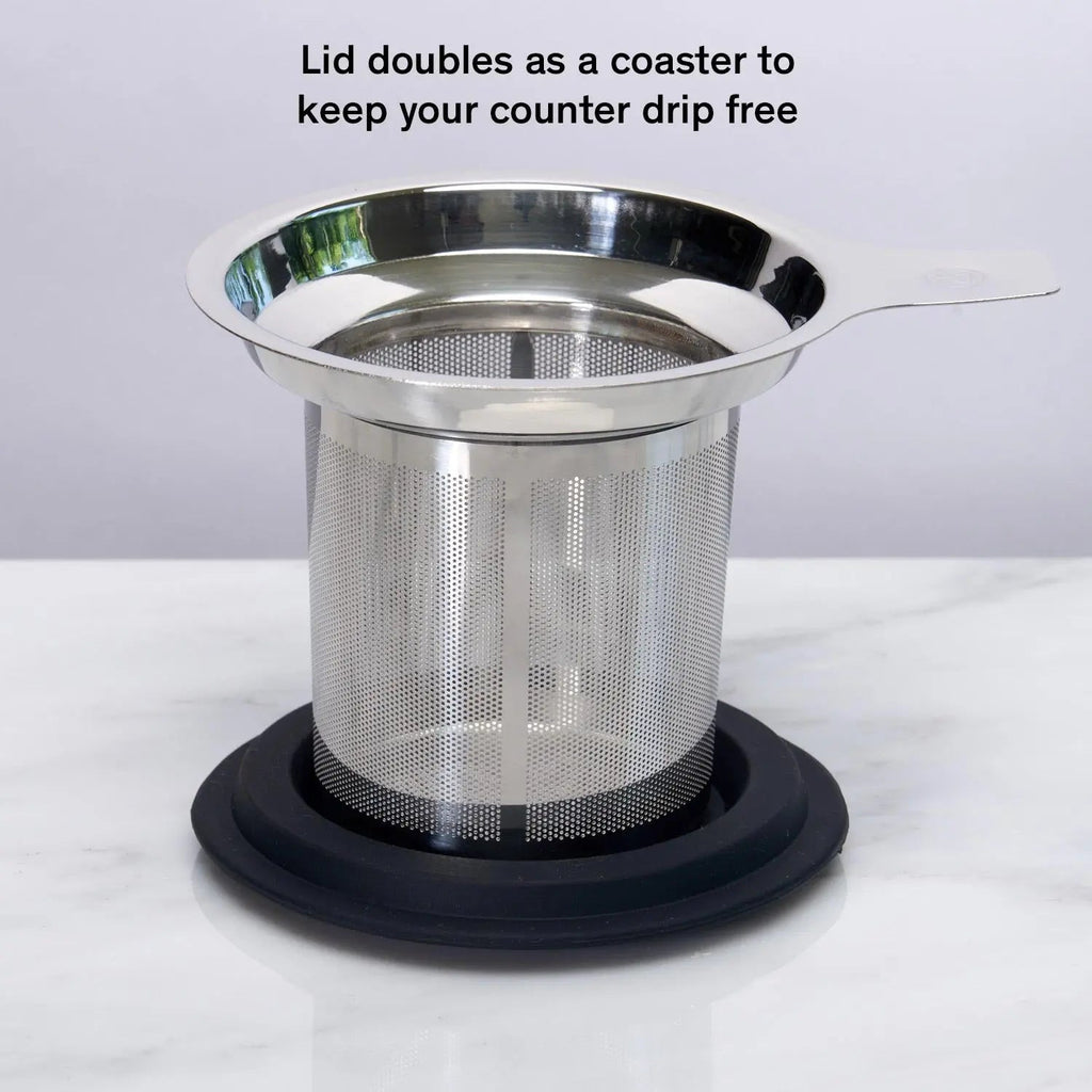 Stainless steel one-cup loose leaf tea infuser resting on its silicone lid coaster beside a ceramic mug