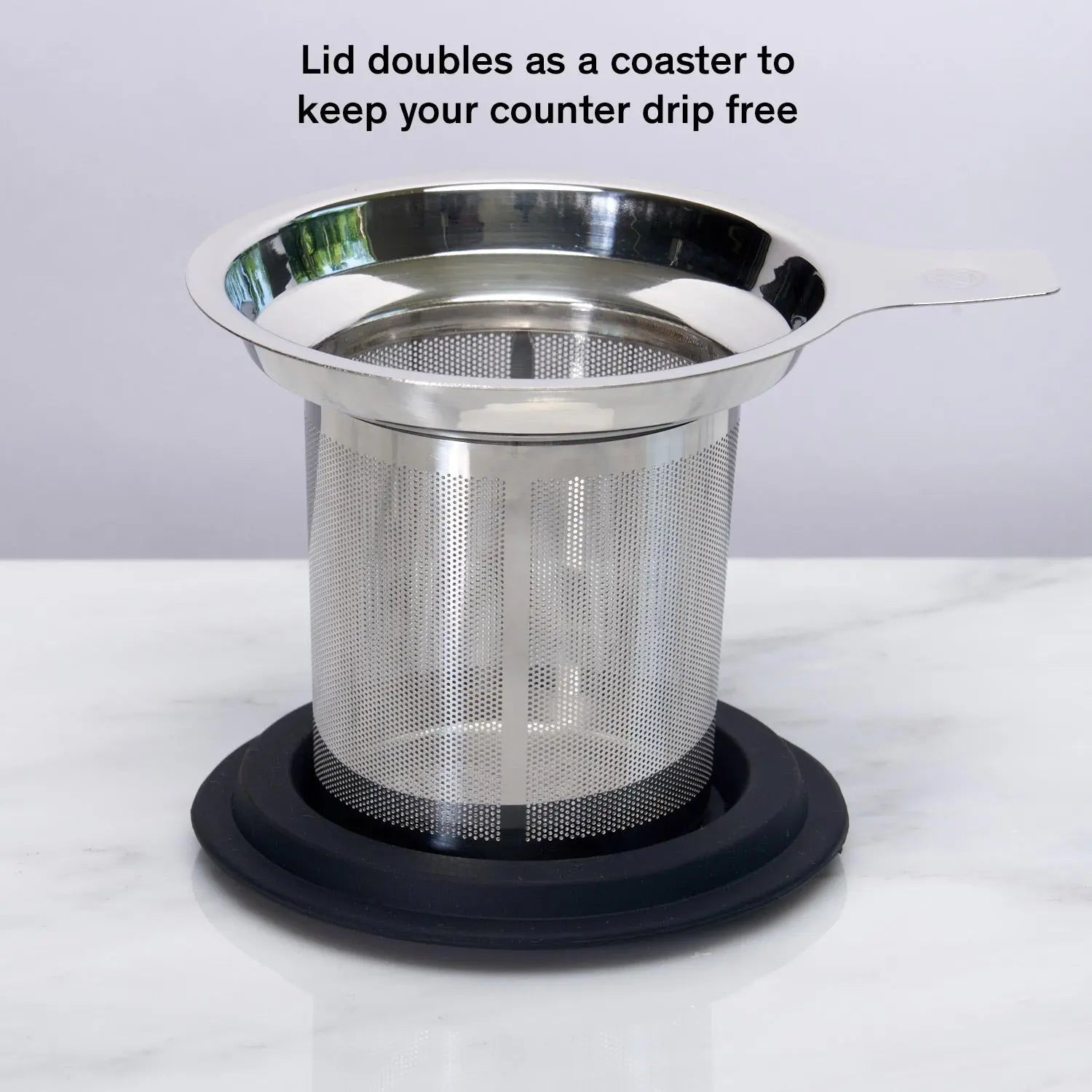 Stainless steel one-cup loose leaf tea infuser resting on its silicone lid coaster beside a ceramic mug