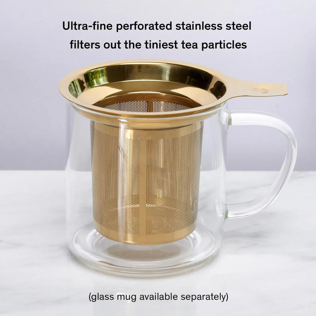 Stainless steel one-cup loose leaf tea infuser resting on its silicone lid coaster beside a ceramic mug