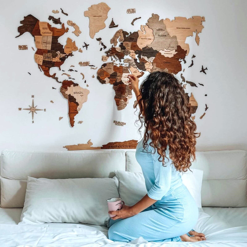 Multicolor 3D layered wooden world map wall art with engraved country names and borders mounted on a neutral wall