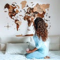Multicolor 3D layered wooden world map wall art with engraved country names and borders mounted on a neutral wall