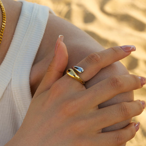 Close-up of a slim 18K gold-plated serpent wrap open ring worn on a finger against a neutral background