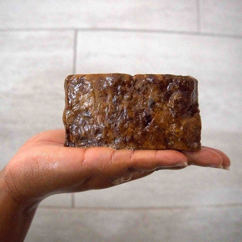 Handcrafted Ghanaian African black soap bar with natural matte texture, shown on a clean surface