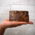 Handcrafted Ghanaian African black soap bar with natural matte texture, shown on a clean surface