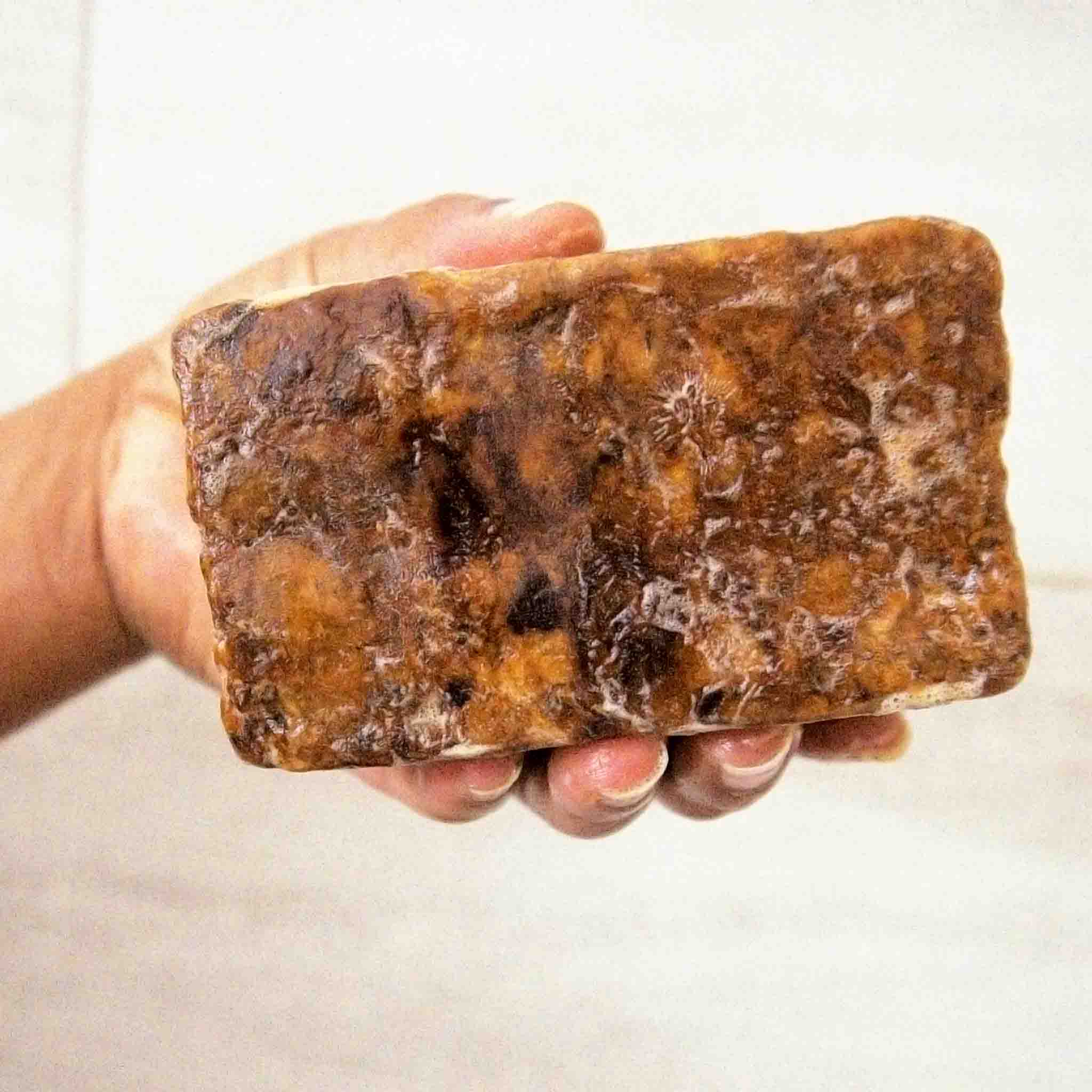 Handcrafted Ghanaian African black soap bar with natural matte texture, shown on a clean surface