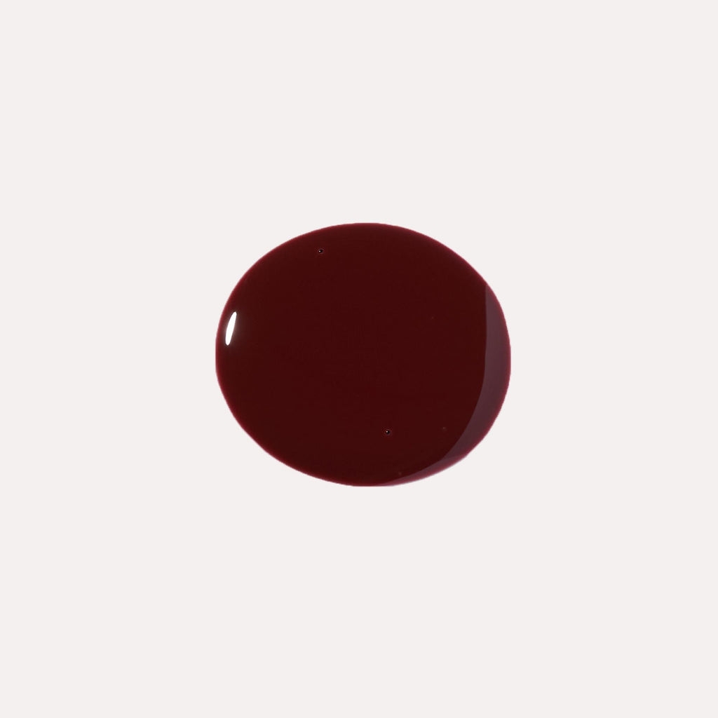 Close-up of tinted lip oil wand resting against soft-focus lips with a glossy, sheer finish