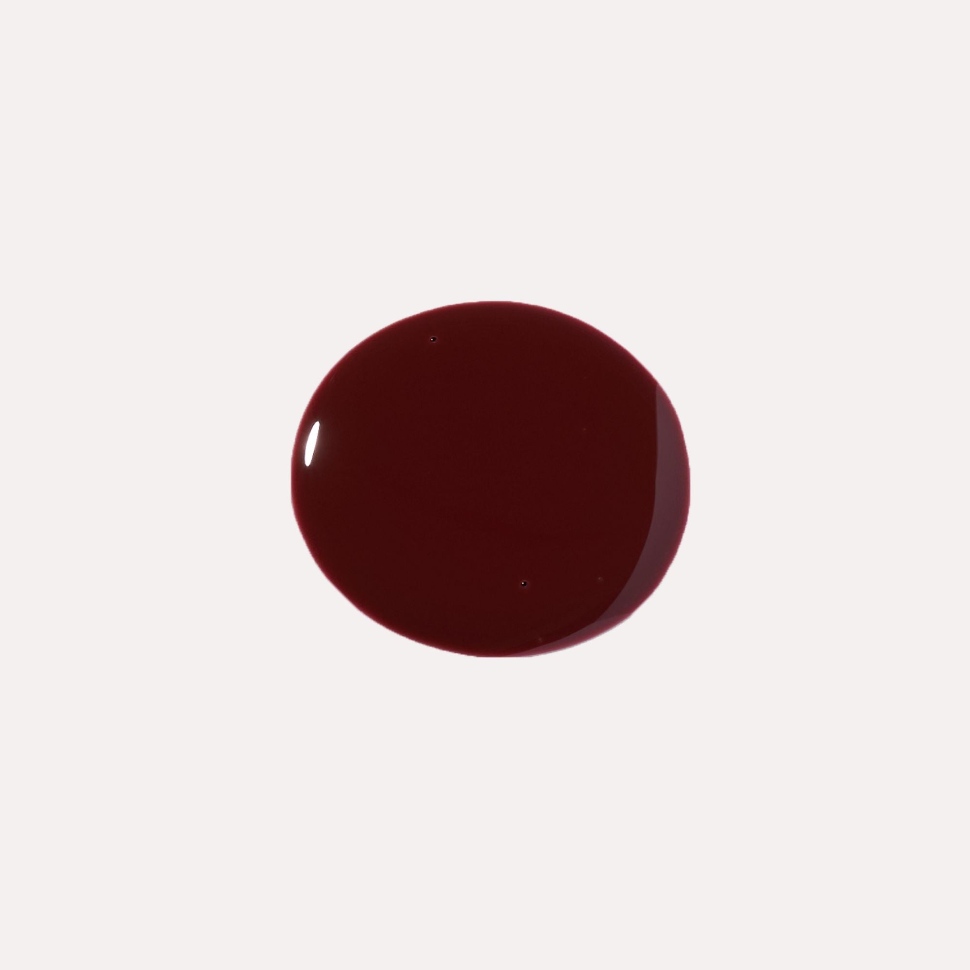 Close-up of tinted lip oil wand resting against soft-focus lips with a glossy, sheer finish