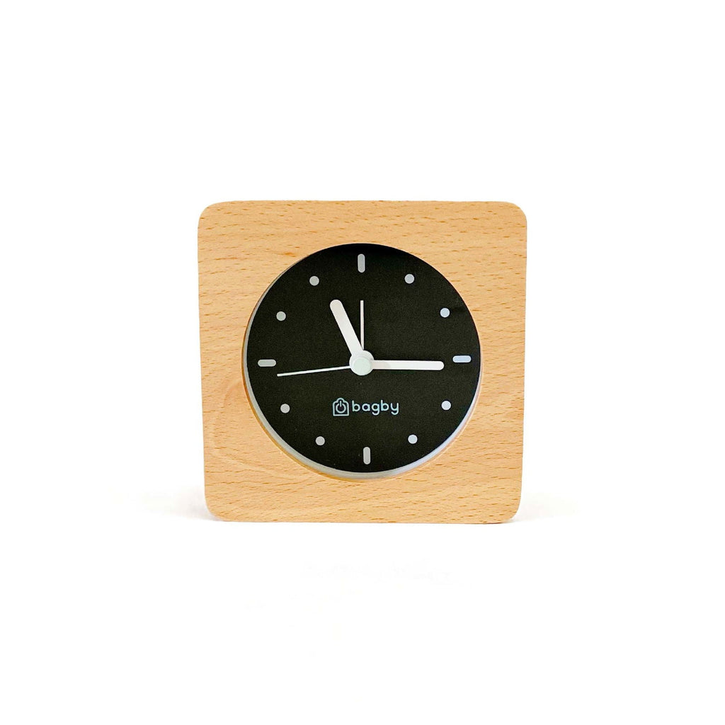 Bagby Minimalist analog alarm clock with solid wood frame and number-free dial on a nightstand