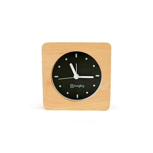 Bagby Minimalist analog alarm clock with solid wood frame and number-free dial on a nightstand