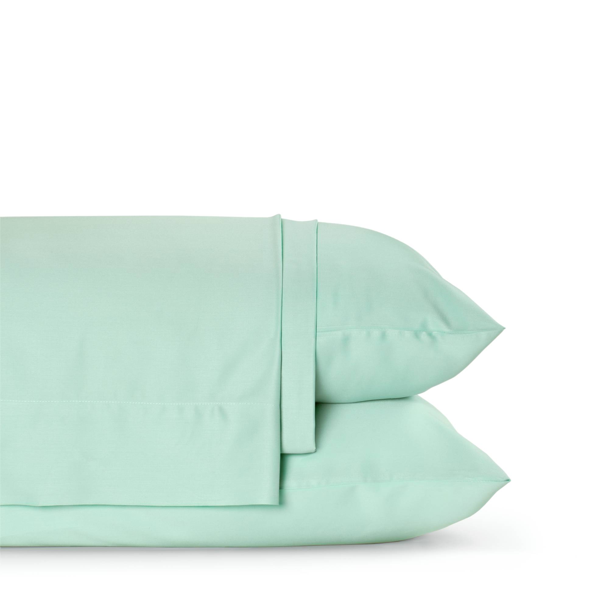 Four-piece bamboo viscose sheet set in neutral tone draped over a neatly made bed, showing silky smooth fabric texture