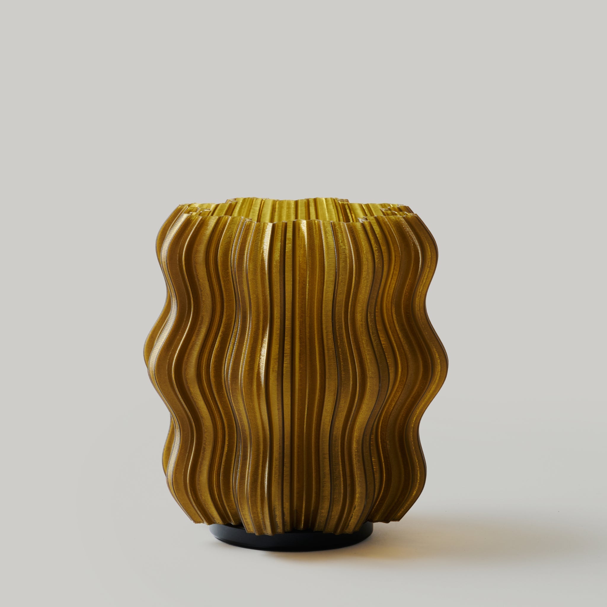 Cordless mini wavy sculptural table lamp with warm glowing filament on a nightstand