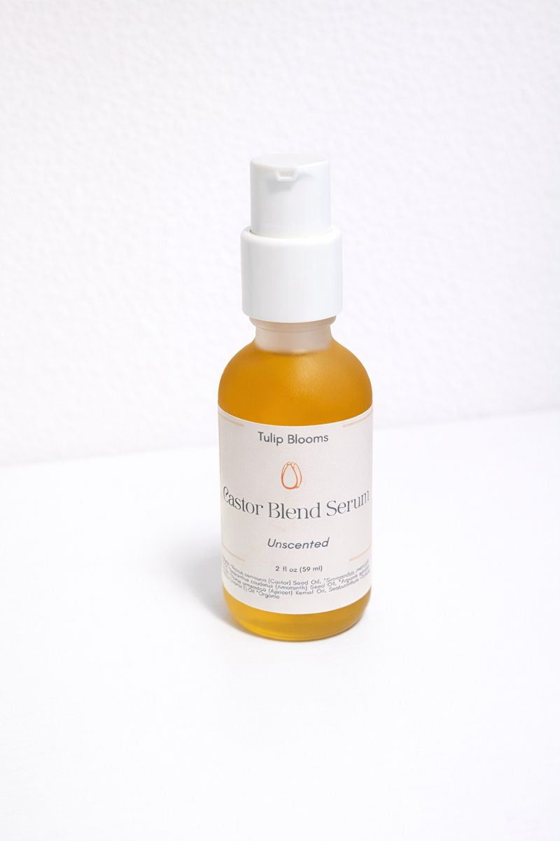 Frosted glass jar of Tulip Blooms Castor Blend oil serum with golden oil visible, shown on a neutral surface