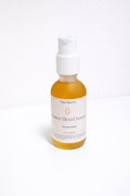 Frosted glass jar of Tulip Blooms Castor Blend oil serum with golden oil visible, shown on a neutral surface