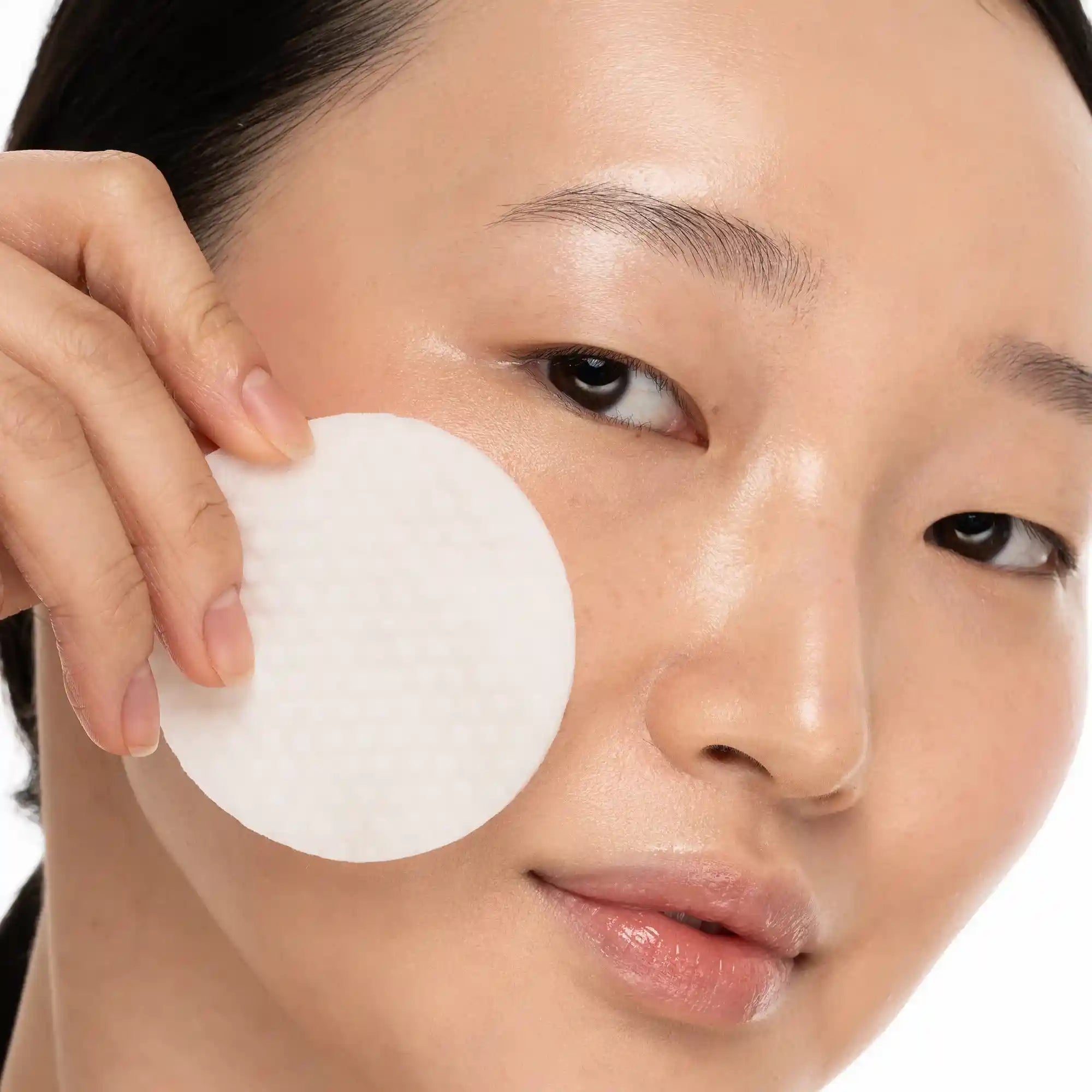 Collagen and retinol toner pads in open jar with a single pad lifted out, showing texture and saturation