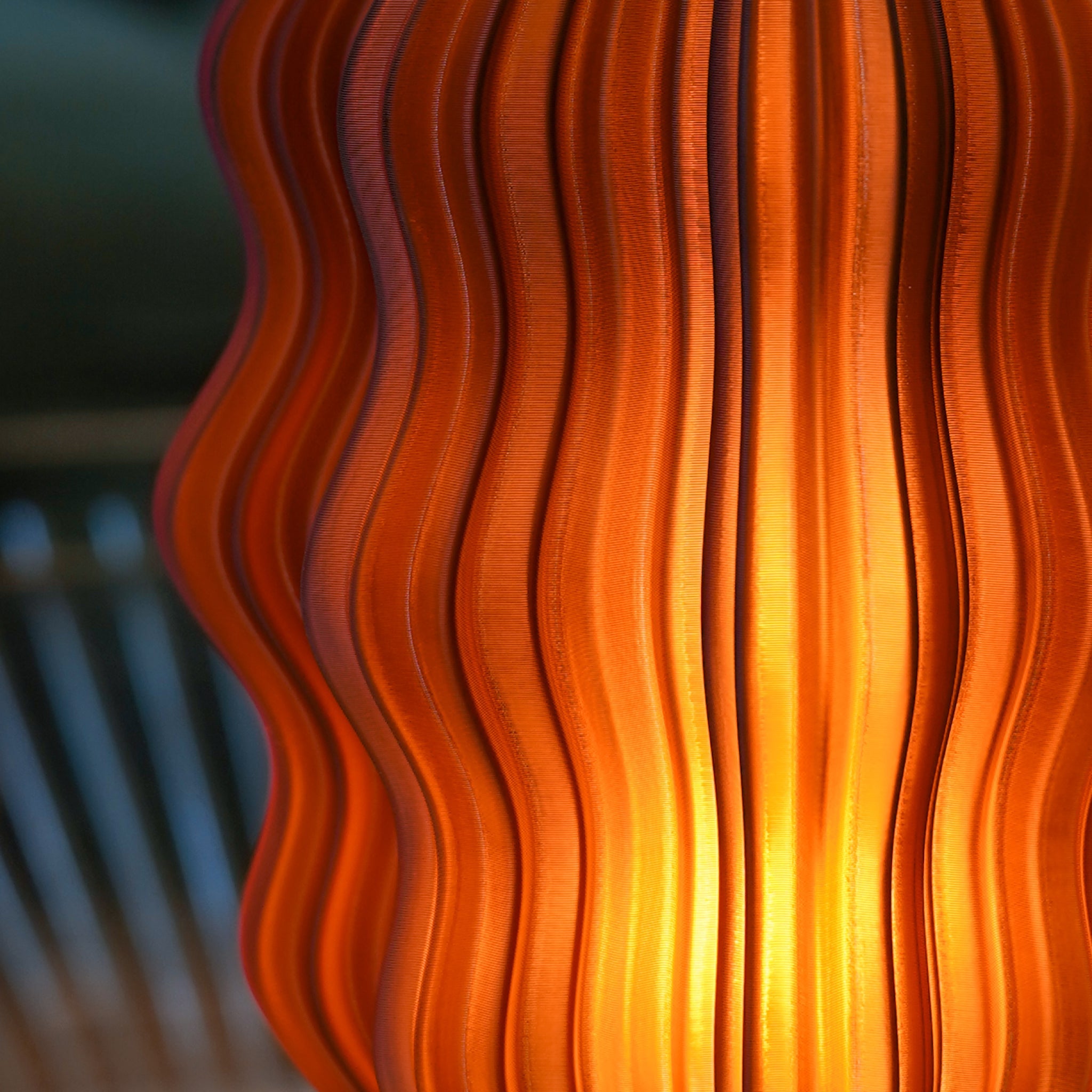 Cordless mini wavy sculptural table lamp with warm glowing filament on a nightstand