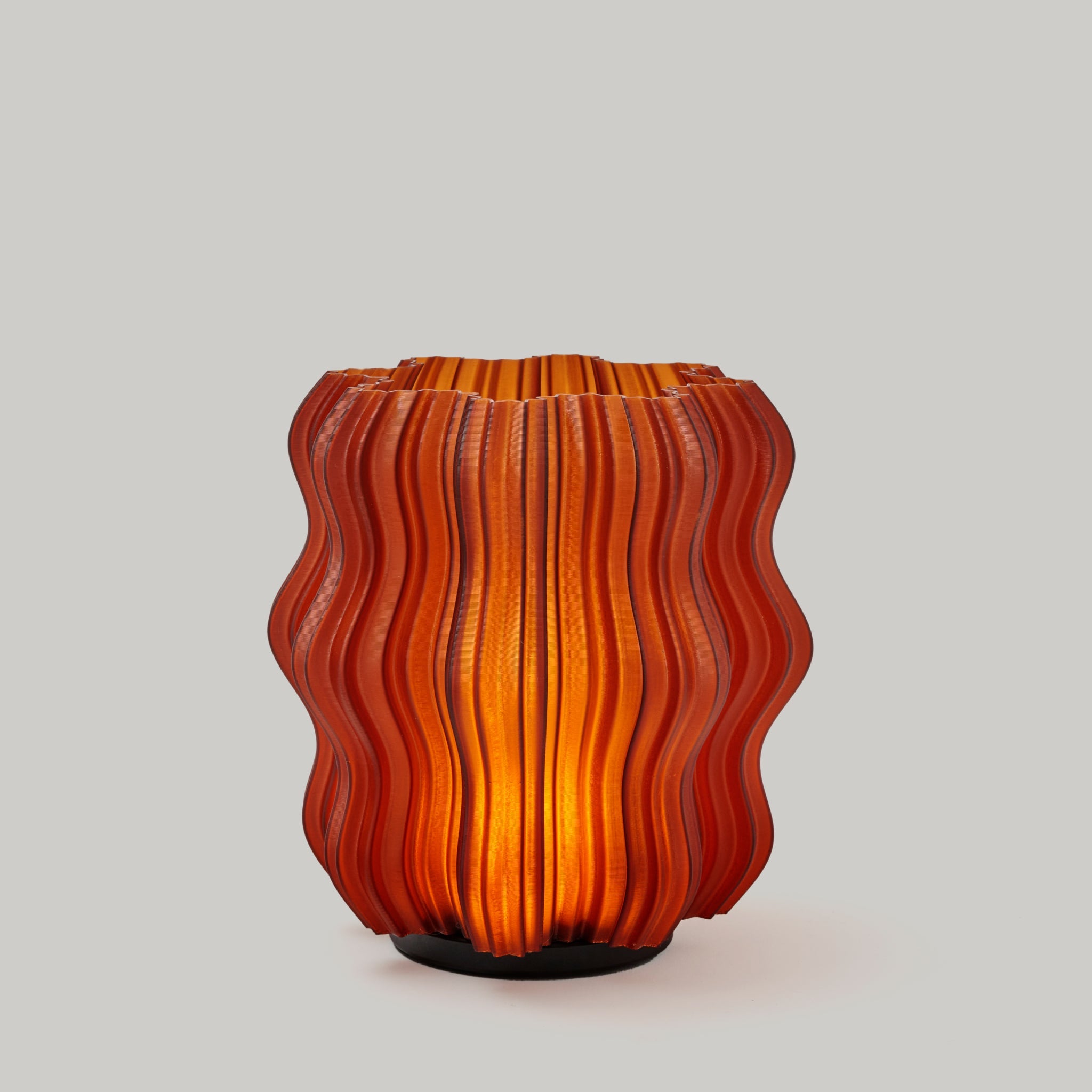 Cordless mini wavy sculptural table lamp with warm glowing filament on a nightstand
