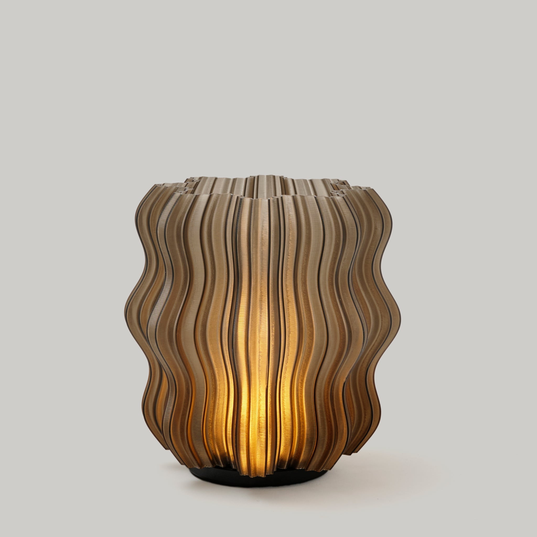 Cordless mini wavy sculptural table lamp with warm glowing filament on a nightstand