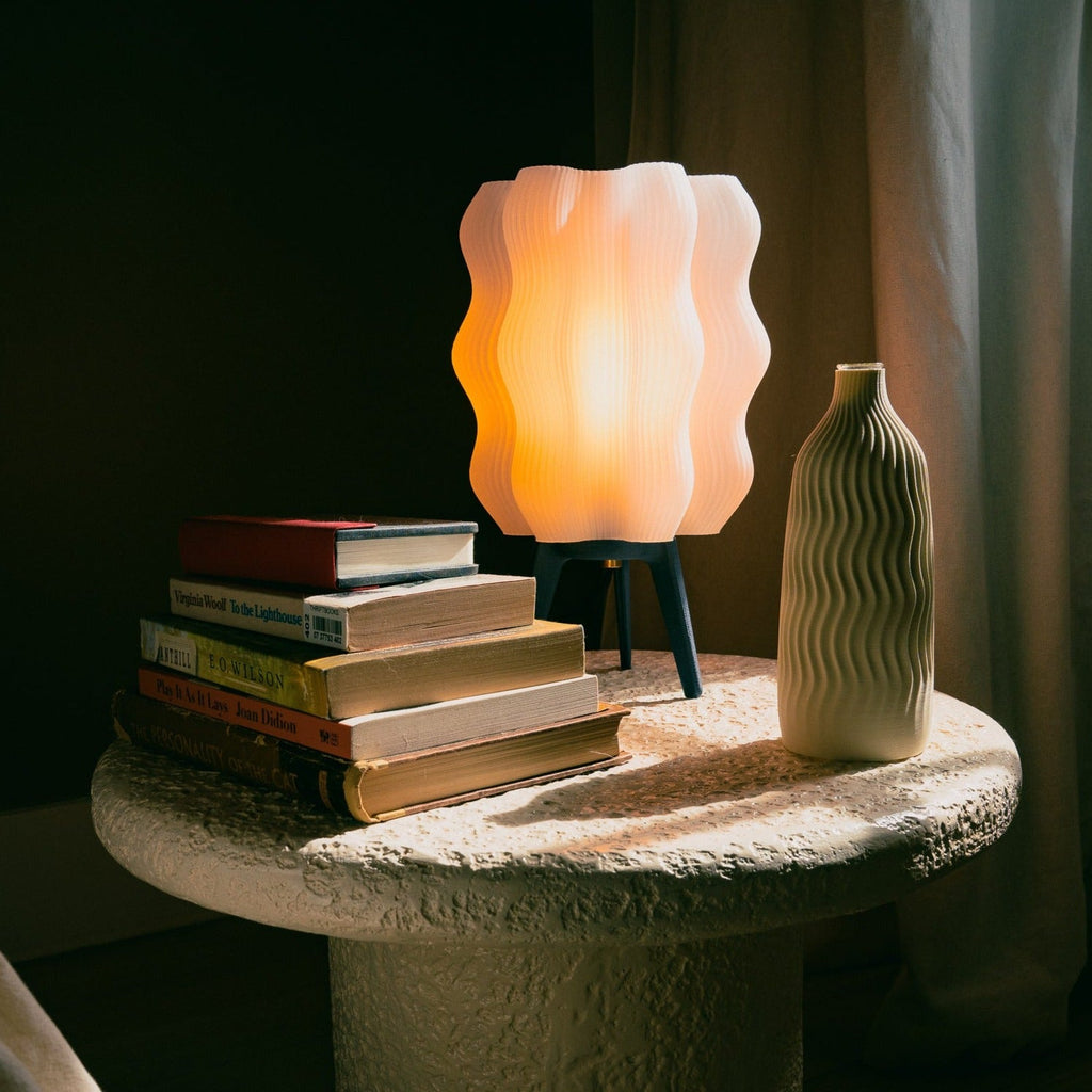 Wavy sculptural table lamp in recycled corn-based plastic with organic rippled silhouette on a flat surface