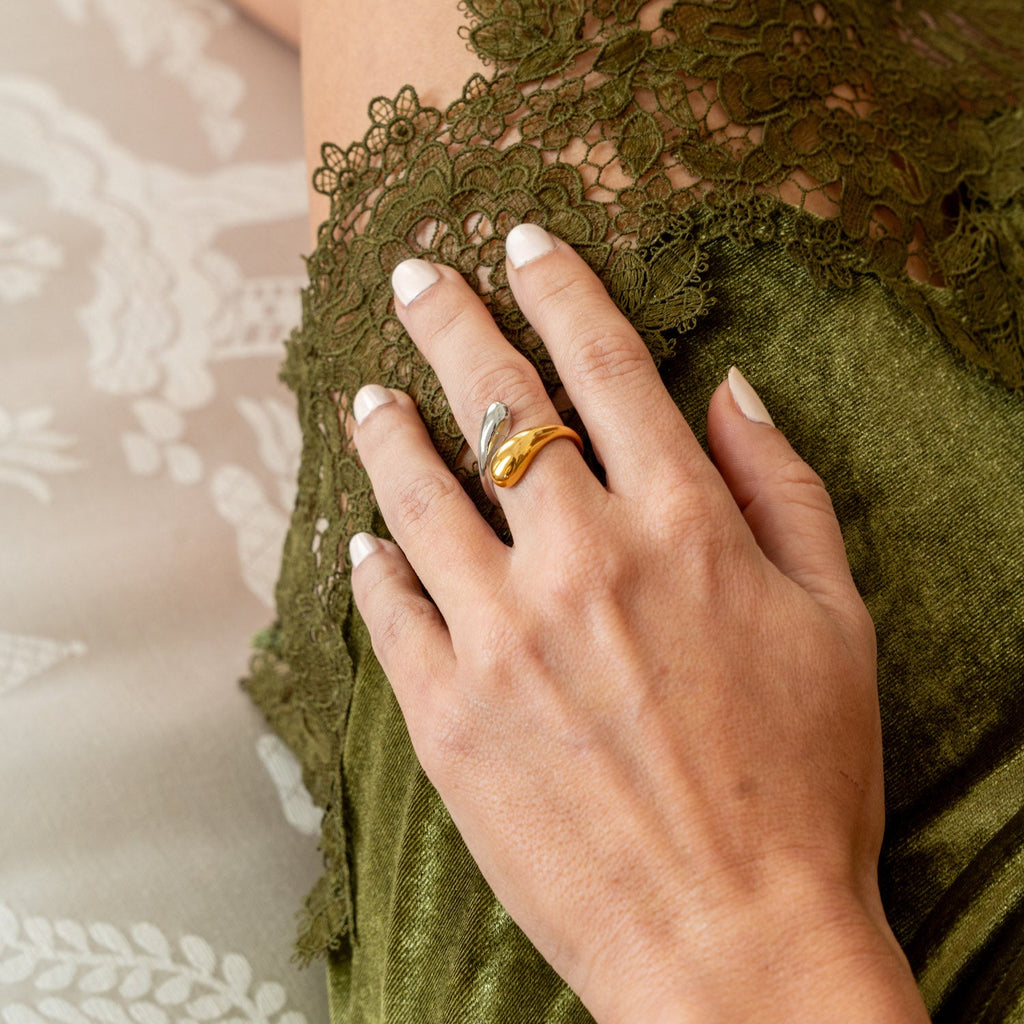 Close-up of a slim 18K gold-plated serpent wrap open ring worn on a finger against a neutral background