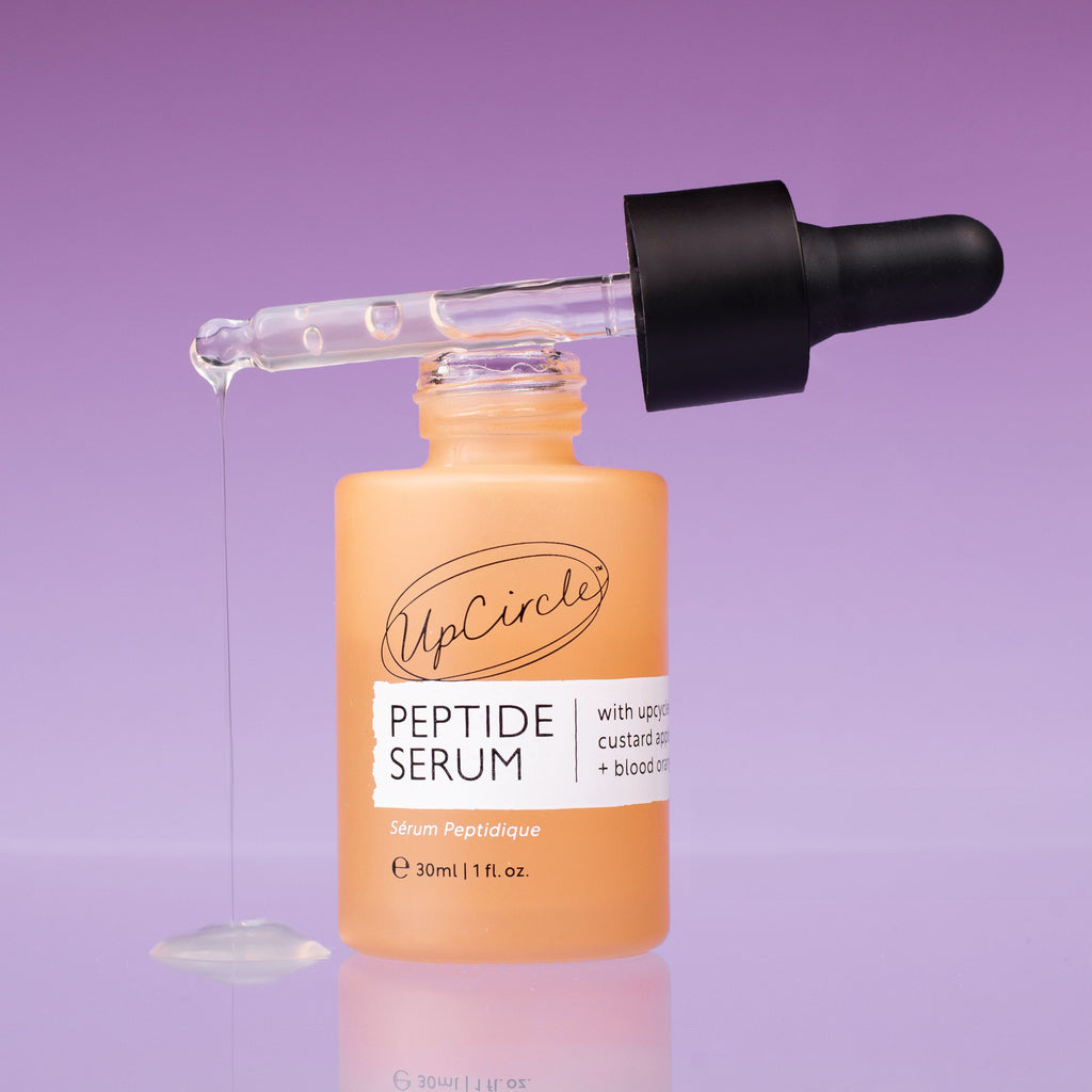 UpCircle Peptide Serum with Custard Apple and Blood Orange in a glass bottle, with a dropper and a skincare background
