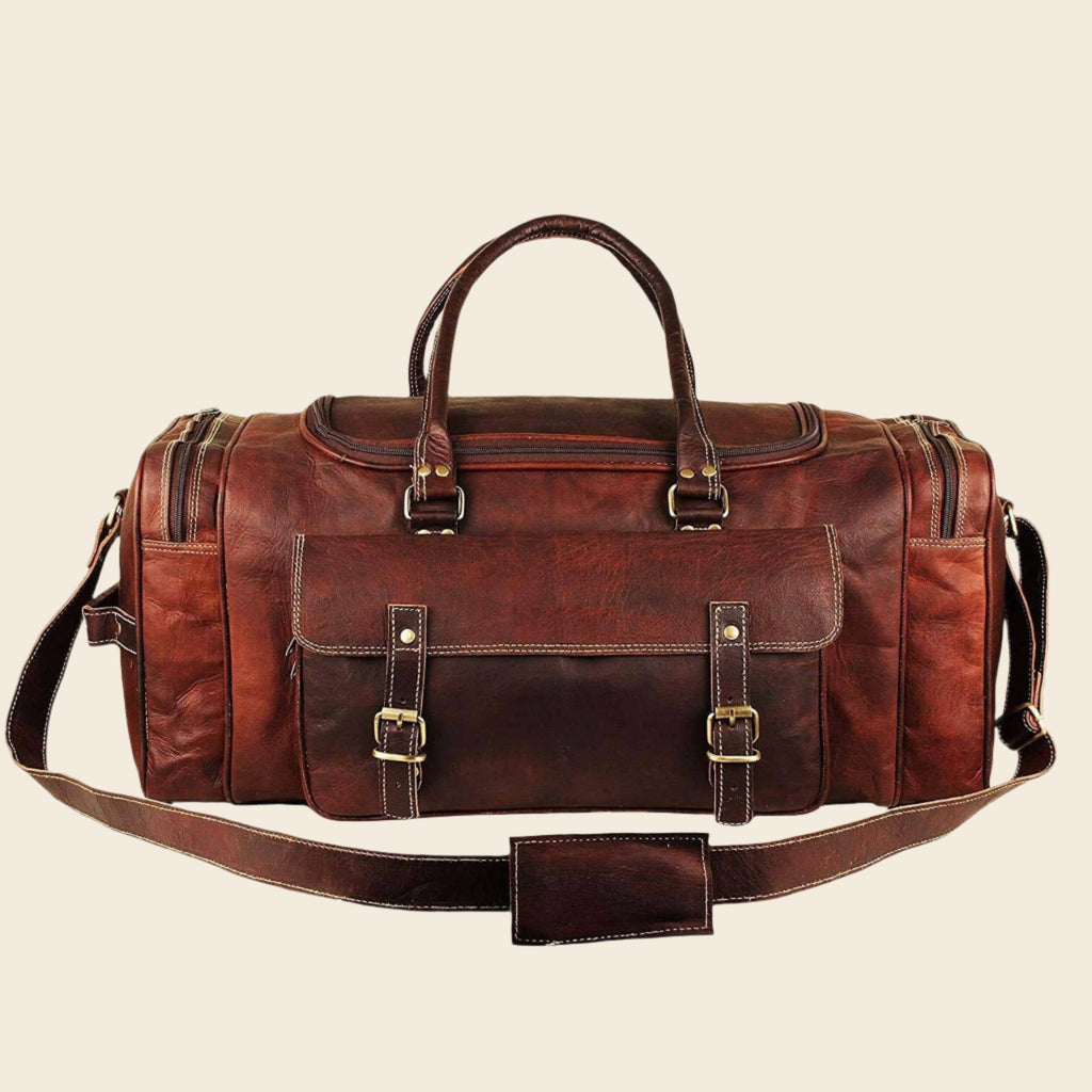 Vintage brown full-grain goat leather weekender duffle bag with brass hardware and matching toiletry bag on neutral background