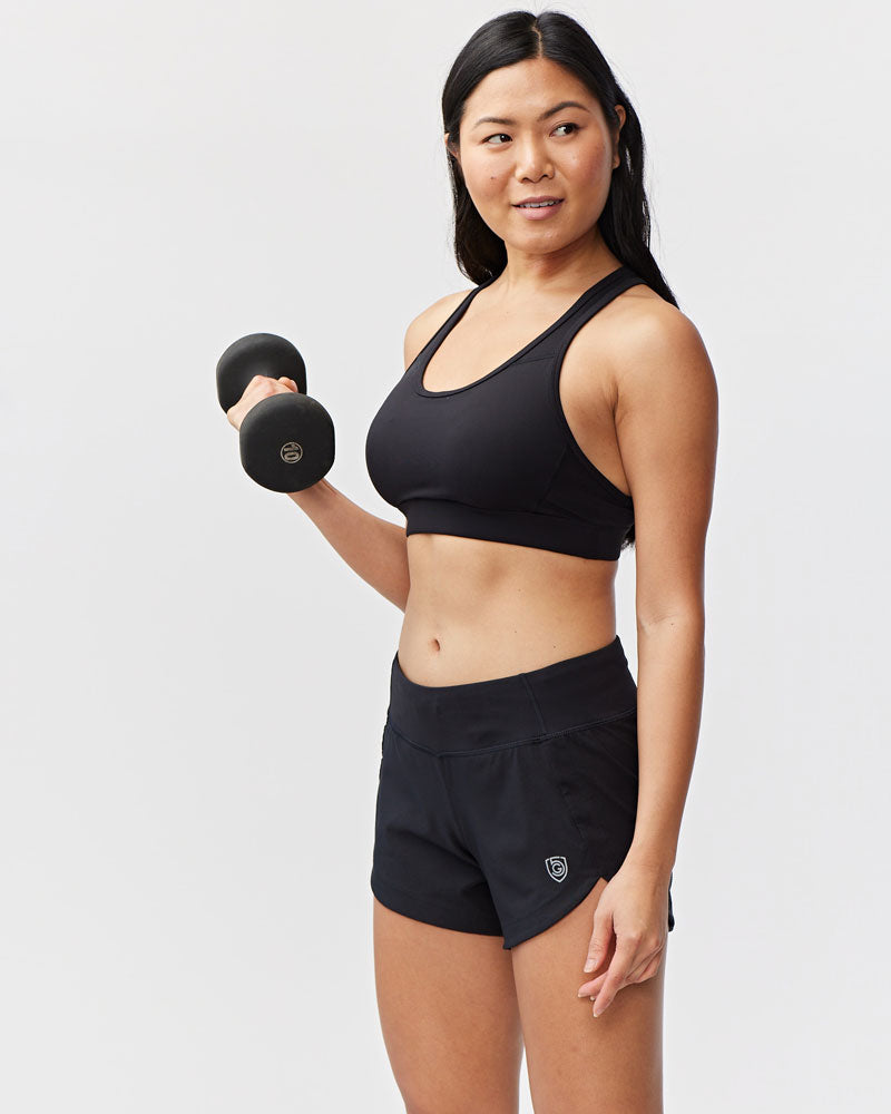 Women's Excel workout shorts in a relaxed training fit, showing extended hem length and waistband pocket detail