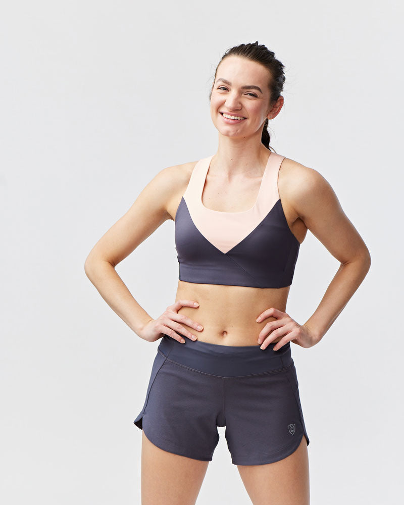 Women's Excel workout shorts in a relaxed training fit, showing extended hem length and waistband pocket detail