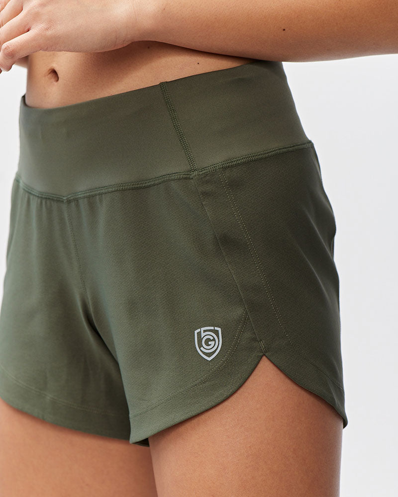 Women's Excel workout shorts in a relaxed training fit, showing extended hem length and waistband pocket detail