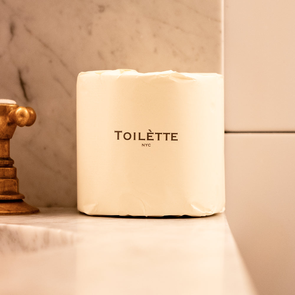 Stack of individually wrapped 100% bamboo toilet paper rolls on a bathroom shelf