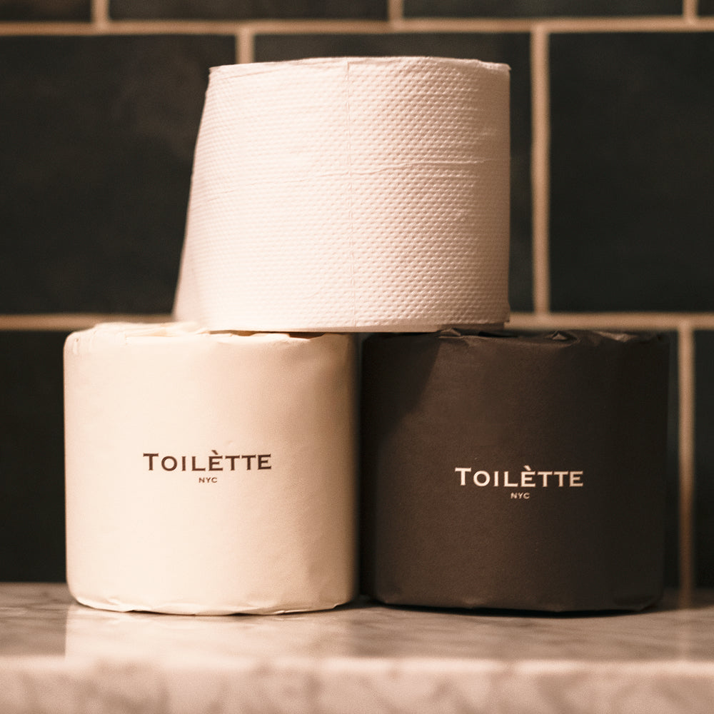 Stack of individually wrapped 100% bamboo toilet paper rolls on a bathroom shelf