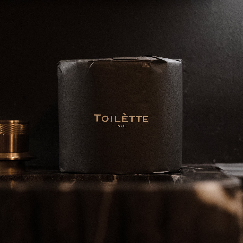 Stack of individually wrapped 100% bamboo toilet paper rolls on a bathroom shelf