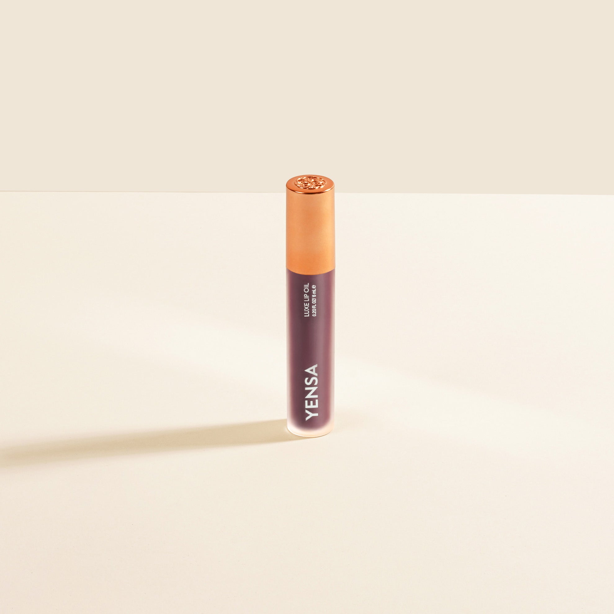 Close-up of tinted lip oil wand resting against soft-focus lips with a glossy, sheer finish