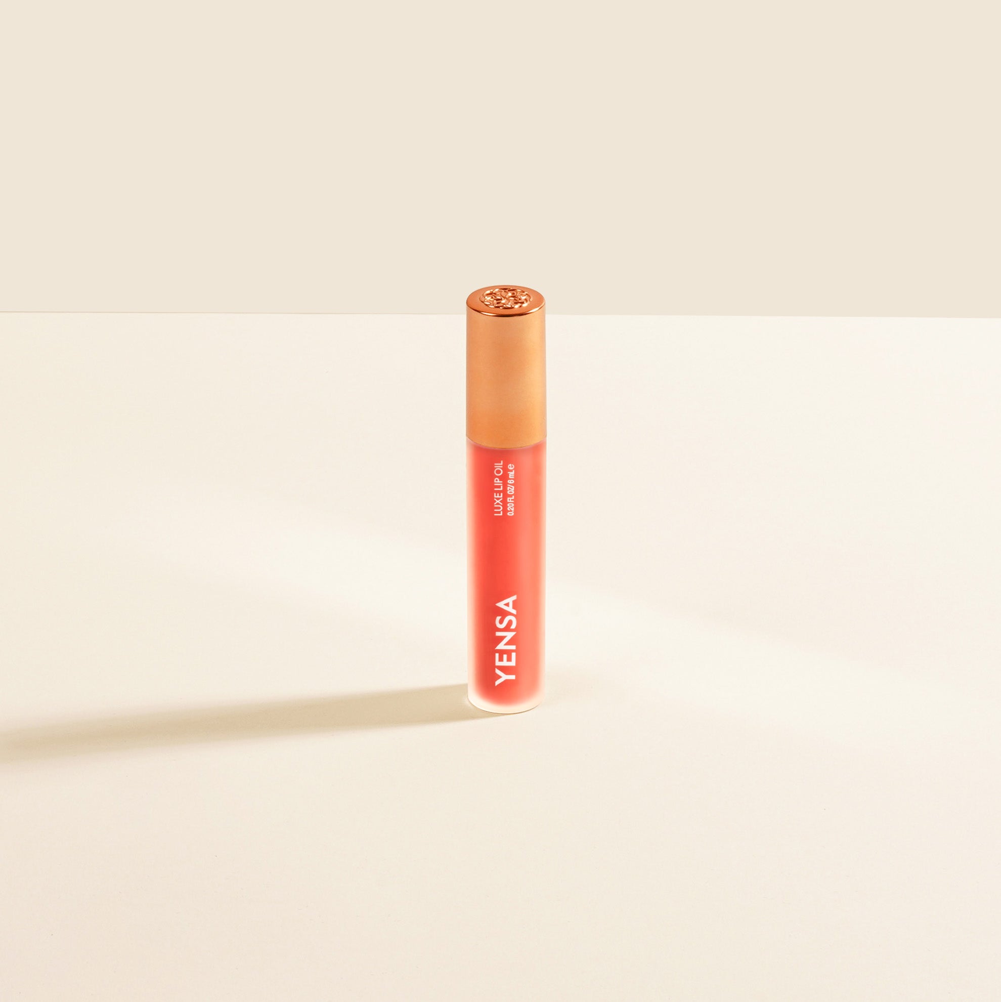 Close-up of tinted lip oil wand resting against soft-focus lips with a glossy, sheer finish