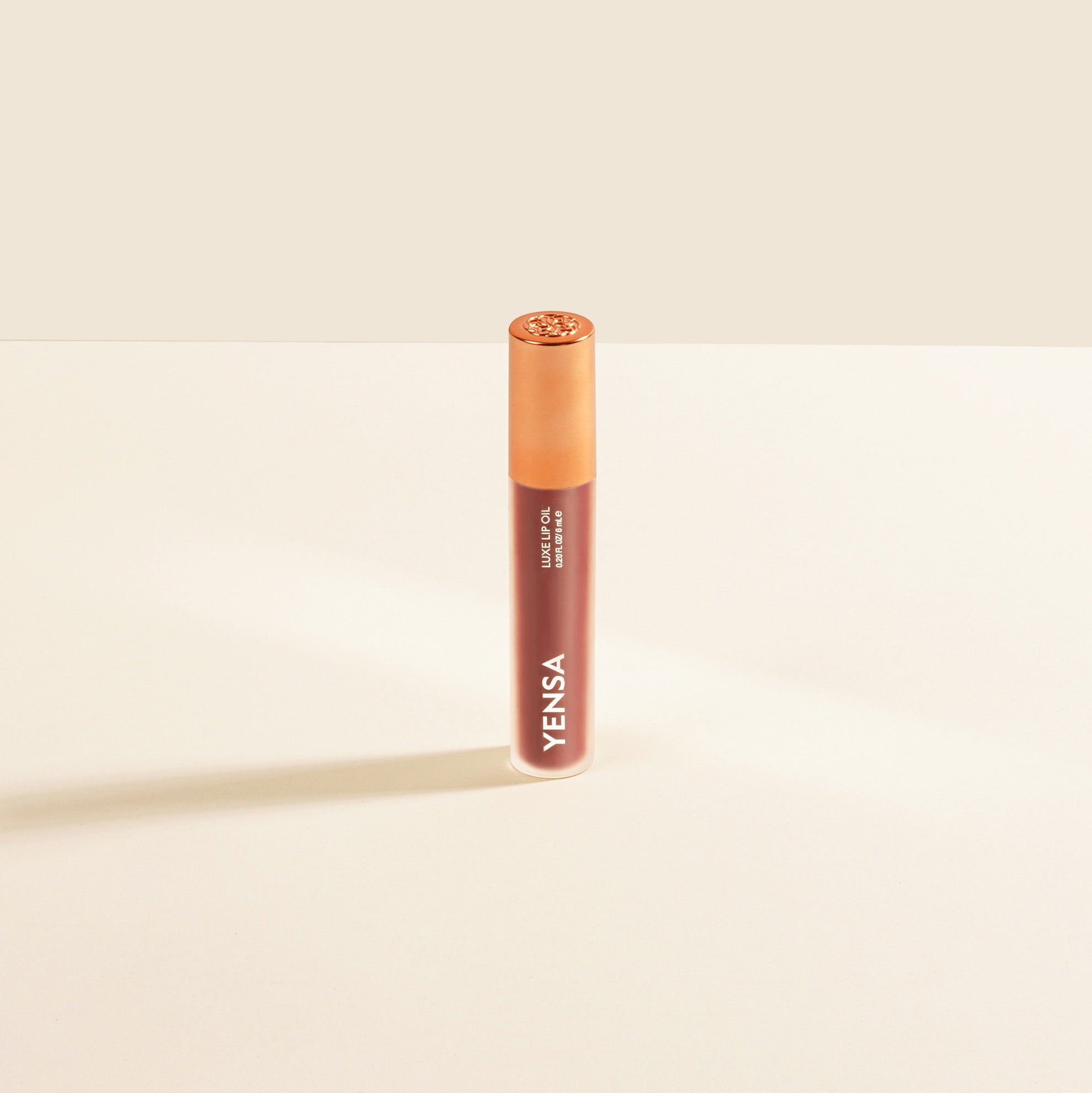 Close-up of tinted lip oil wand resting against soft-focus lips with a glossy, sheer finish