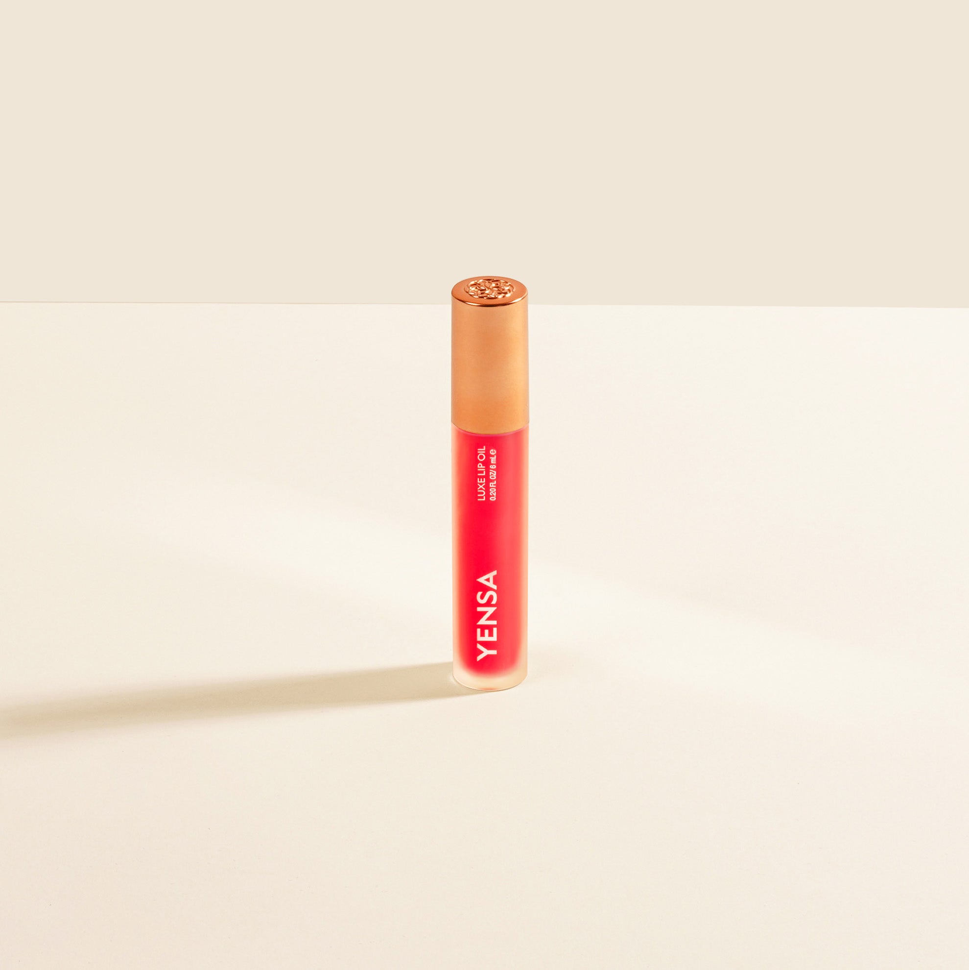 Close-up of tinted lip oil wand resting against soft-focus lips with a glossy, sheer finish