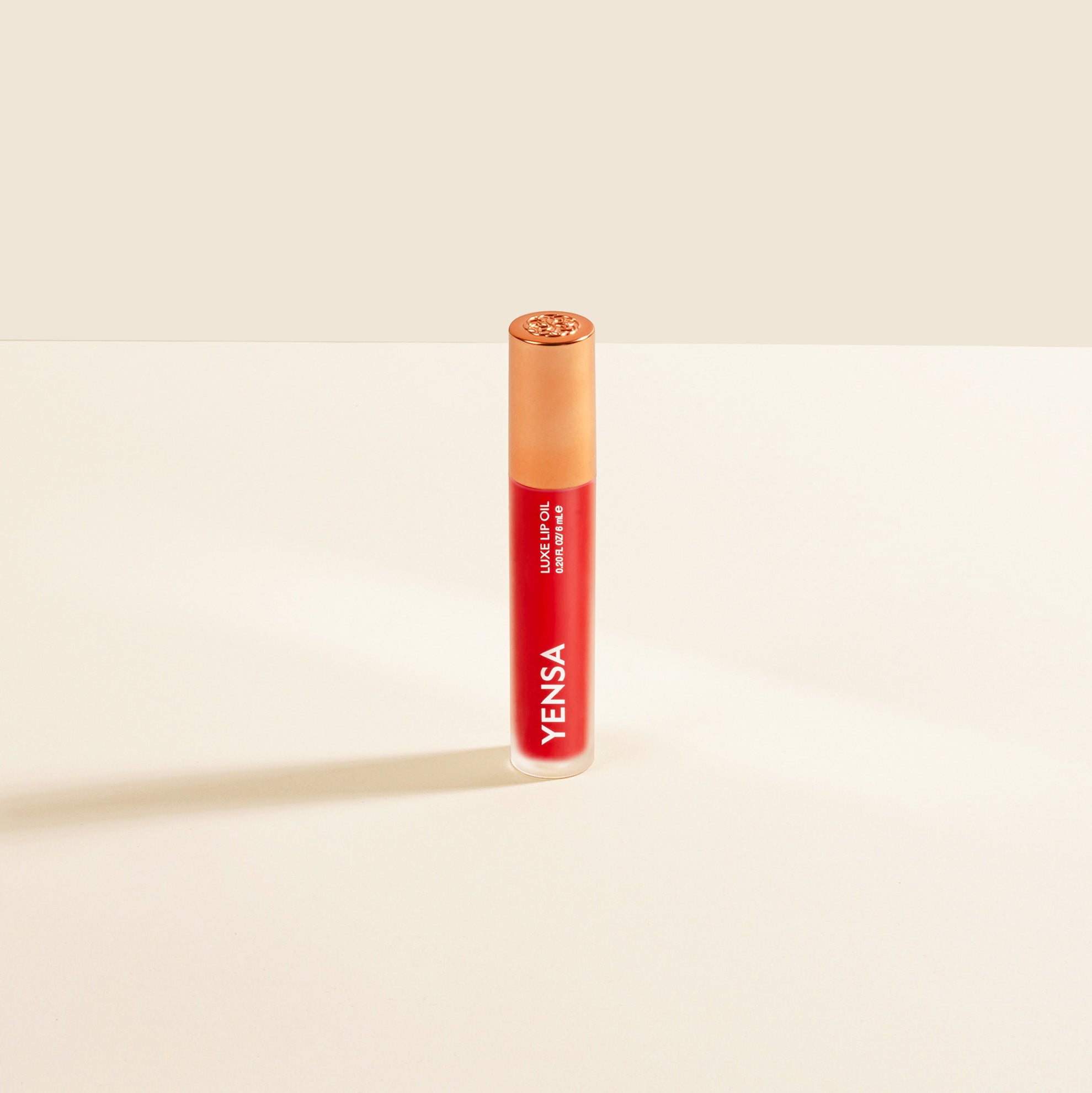 Close-up of tinted lip oil wand resting against soft-focus lips with a glossy, sheer finish