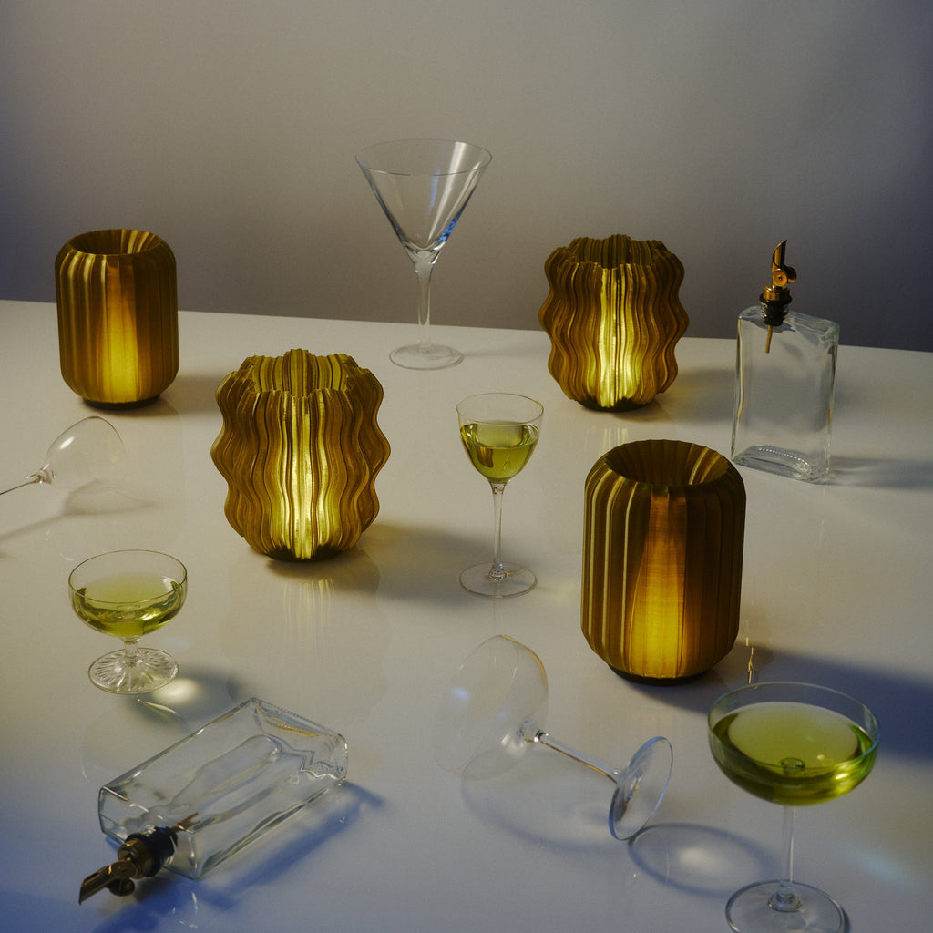 Cordless mini wavy sculptural table lamp with warm glowing filament on a nightstand