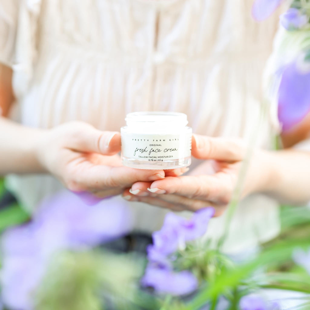 Small glass jar of tallow anti-aging face moisturizer with black lid on a clean surface