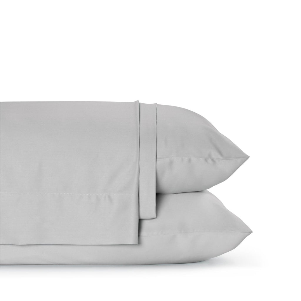 Four-piece bamboo viscose sheet set in neutral tone draped over a neatly made bed, showing silky smooth fabric texture