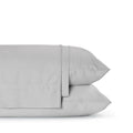 Four-piece bamboo viscose sheet set in neutral tone draped over a neatly made bed, showing silky smooth fabric texture
