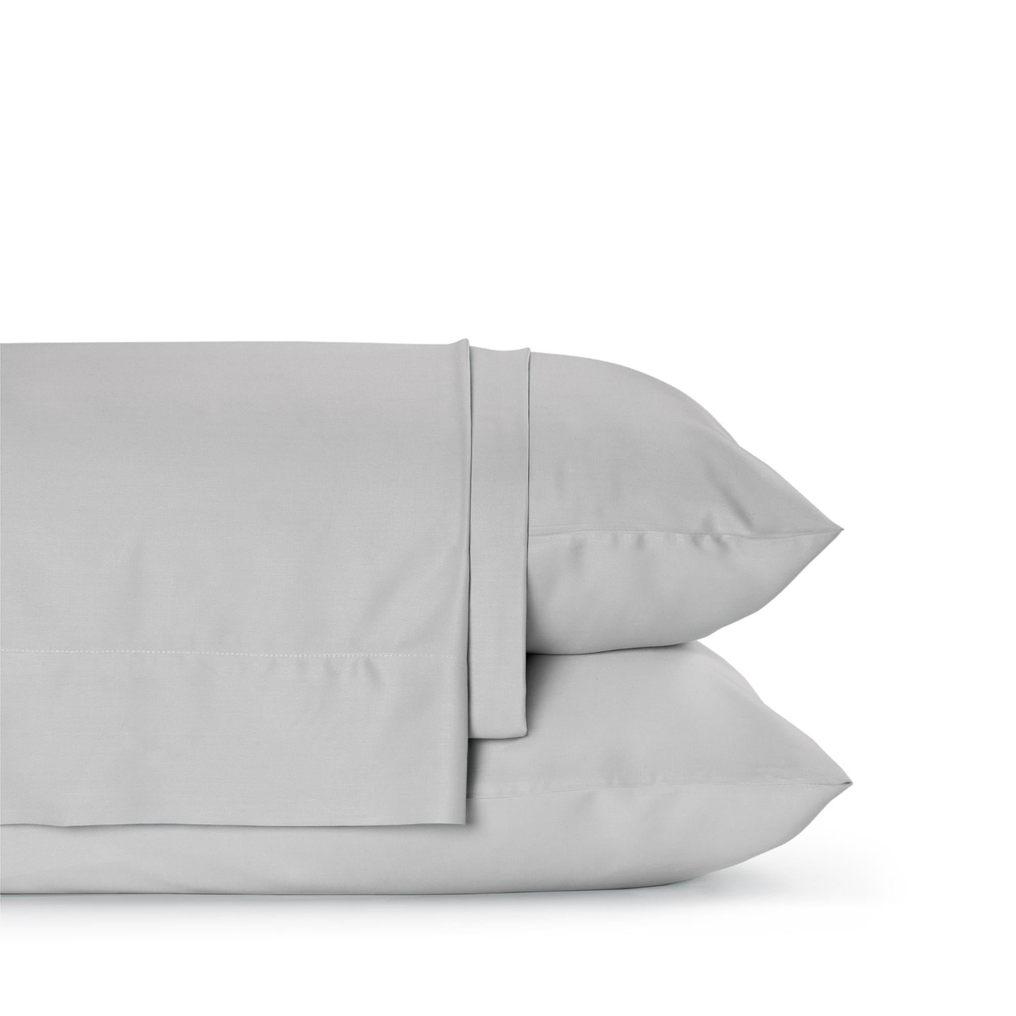 Four-piece bamboo viscose sheet set in neutral tone draped over a neatly made bed, showing silky smooth fabric texture