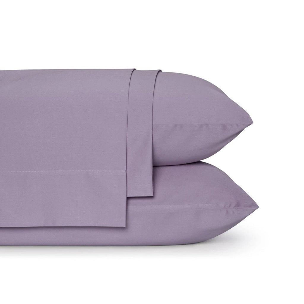 Four-piece bamboo viscose sheet set in neutral tone draped over a neatly made bed, showing silky smooth fabric texture