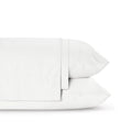 Four-piece bamboo viscose sheet set in neutral tone draped over a neatly made bed, showing silky smooth fabric texture