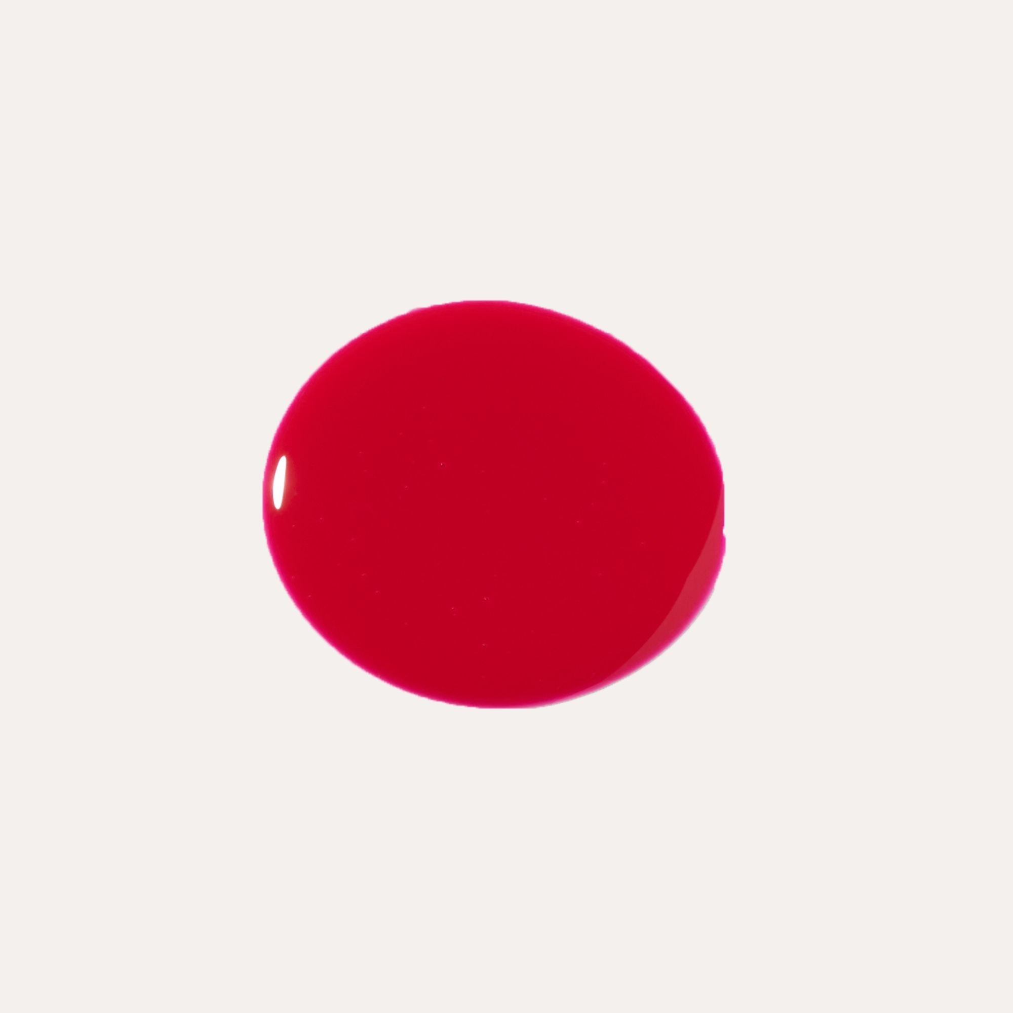 Close-up of tinted lip oil wand resting against soft-focus lips with a glossy, sheer finish