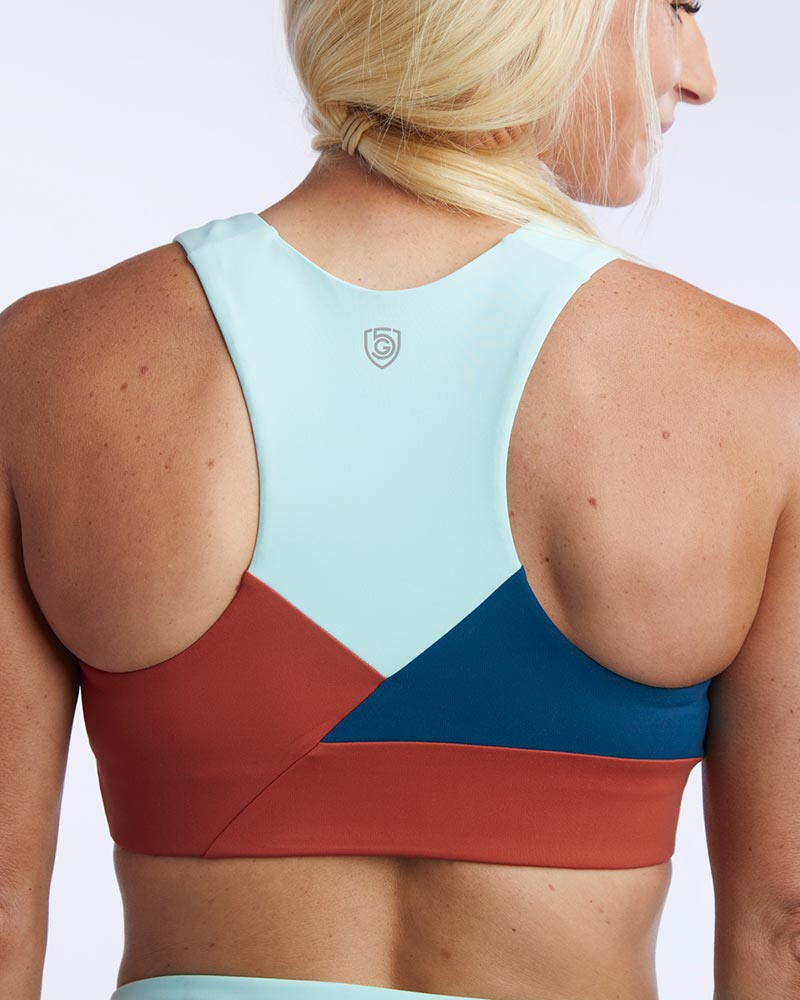 Pionxr color-block sports bra top with flat seam construction and longer cropped length in bold two-tone colorway