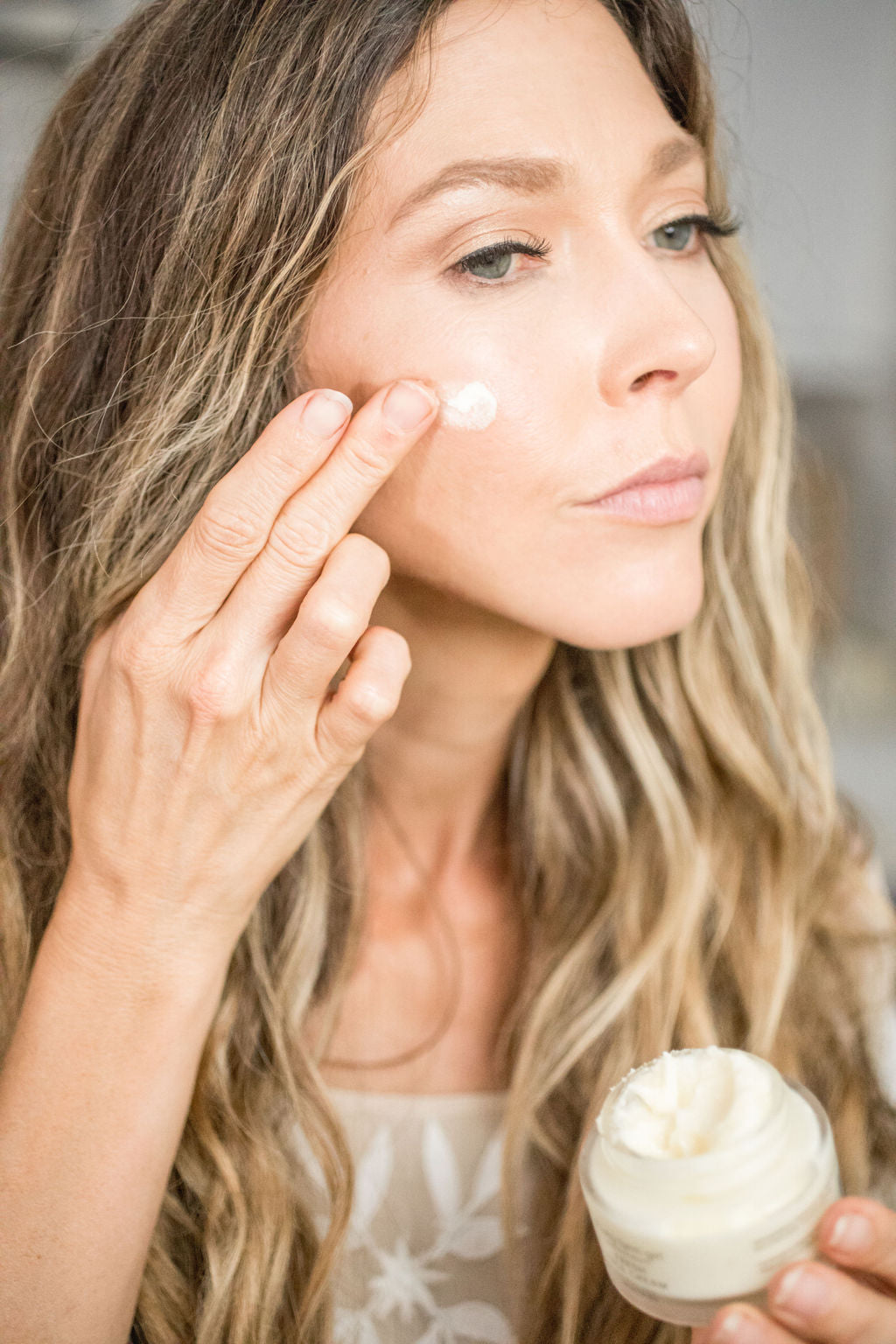Small glass jar of tallow anti-aging face moisturizer with black lid on a clean surface