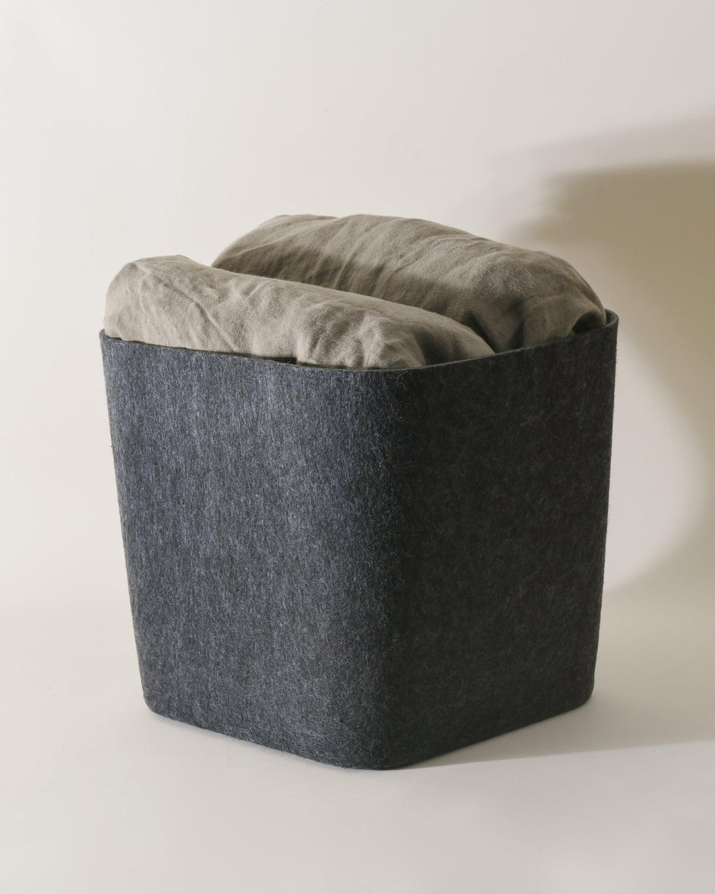 SortJoy Sculpted Storage Bin in Carbon colorway, structured shape on a shelf holding folded linens